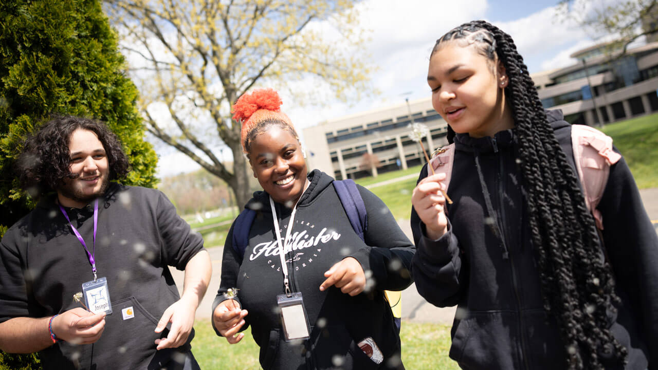 QUADS students take a photo blowing dandelions.